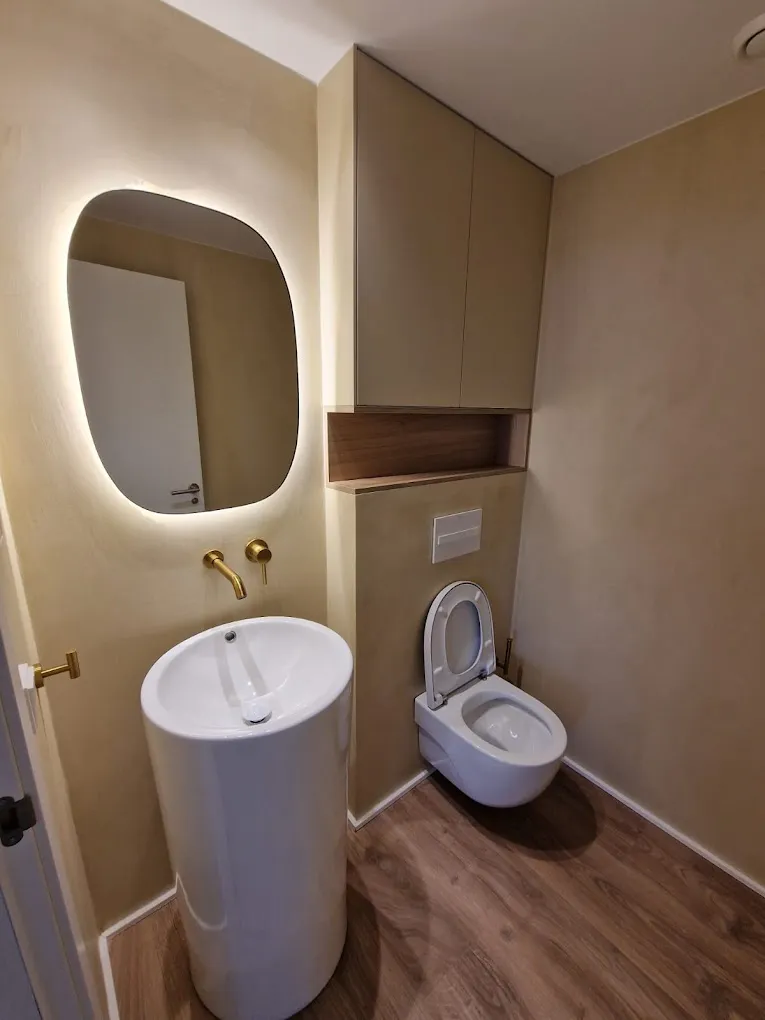 Aseo con lavabo de pie, grifo dorado empotrado y espejo con luz